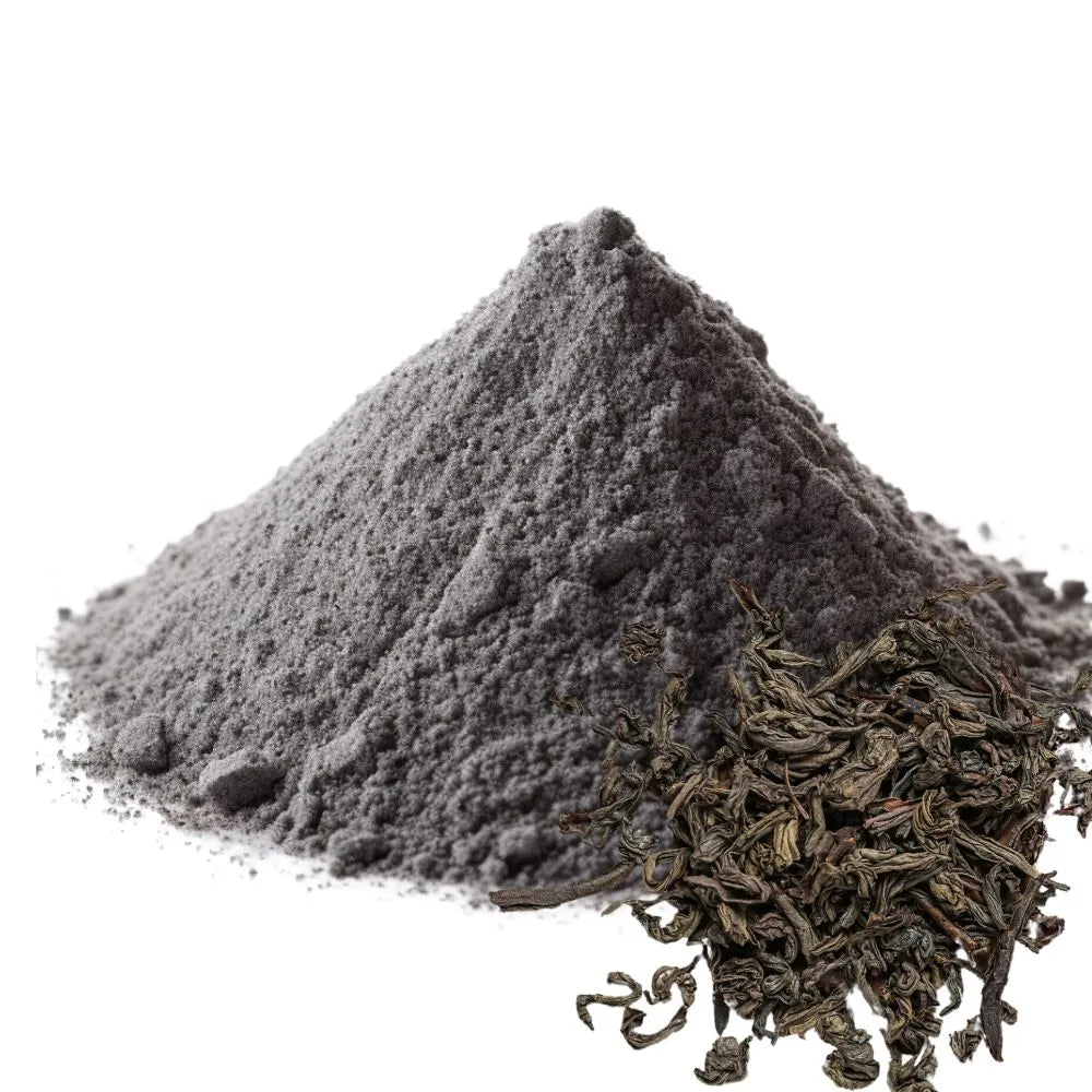 Dark gray pu-erh tea powder piled high, alongside dried pu-erh tea leaves, isolated on a white background for WowNutri.