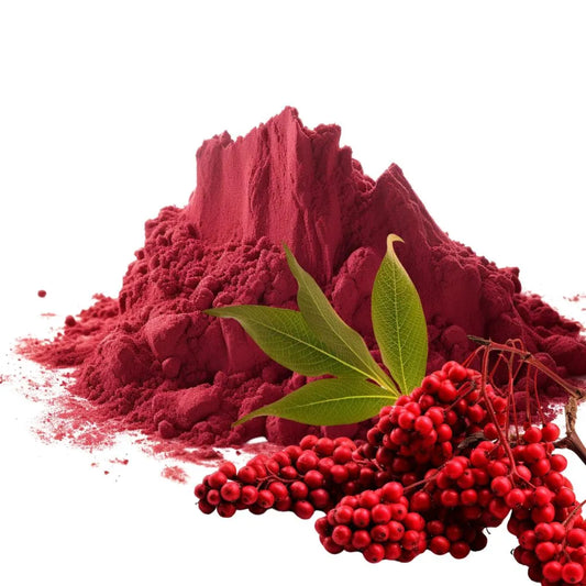 Heaped pile of vibrant red Sumac powder with fresh Sumac berries and green leaves on a white background - WowNutri